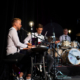 Das Bild zeigt die Band WeChazz, im Vordergrund ein Klavierspieler, im Hintergrund Gitarrist und Schlagzeuger